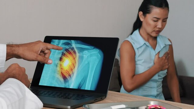 Doctor showing x-ray of pain in the heart on a laptop with woman patient. Heart attack symptoms