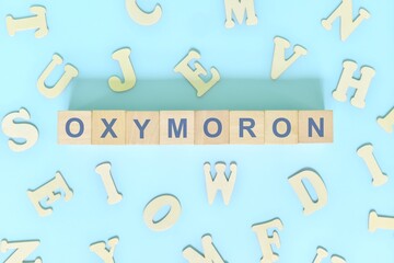 Oxymoron figure of speech concept in English grammar class lesson. Wooden blocks typography flat lay in blue background.
