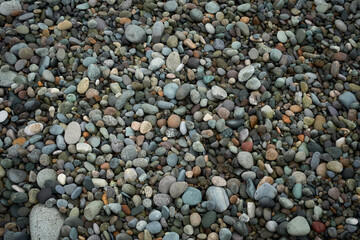 Abstract background texture of random sizes of stones and colored smooth pebbles on the seashore
