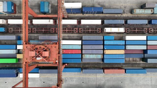 Cargo station in the city with cargo containers. Drone aerial view. Top view of cargo in the train station, rows of containers, crane on top.  Economy, transportation, business concept b-roll footage.