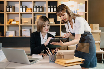 Starting small businesses SME owners, two woman check online orders Selling products working with boxs freelance work at office using tablet and laptop  marketing, packaging, concept