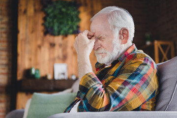 Photo of unhappy tired retired man dressed plaid shirt arm head having head ache sitting couch...