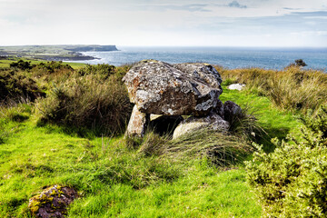 Exposed chamber and capstone of Magheraboy prehistoric passage mound burial above White Park Bay....