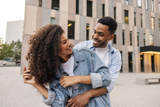 Cute young african couple in love are relaxing outdoors enjoying each other. Brunette guy and girl wear casual clothes. Sincere emotions lifestyle concept