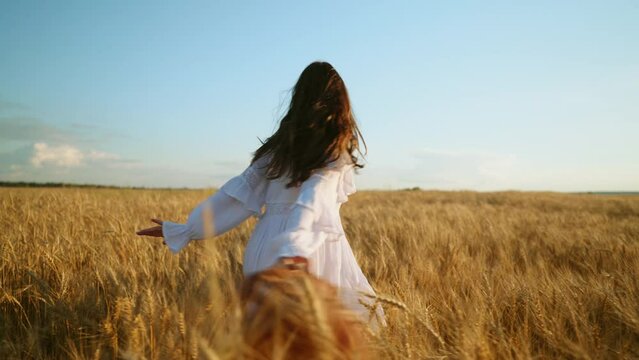 freedom loving and carefree woman is running and whirling on golden rye field in summer, slow motion