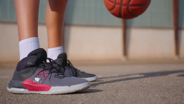 Close-up of sportswoman bouncing basketball ball training on ground floor of the court. Basketball player. Workout. Sport activities. Entertainment.