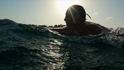 Athletic Young man professional triathlon swimmer practicing at morning sea. Ocean swim slow motion shot - Powered by Adobe