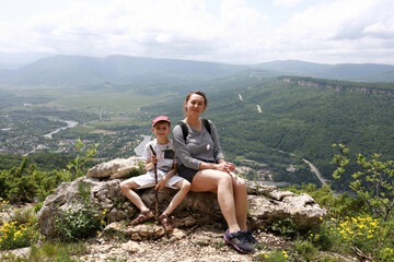 Mother with her son resting on rock of Una-koz ridge in Caucasus