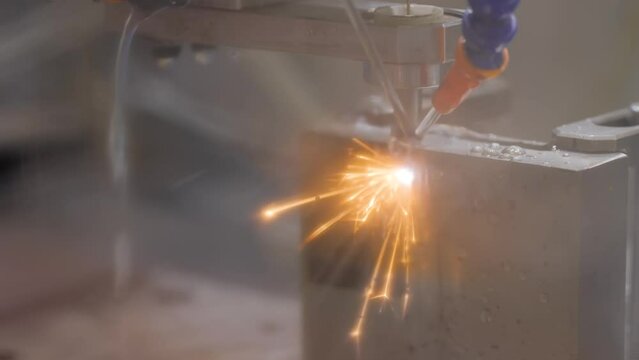 Wire cutting machine working with metal workpiece with sparks at factory, exhibition, plant - close up. Metalworking, industrial, machining, technology, manufacturing and equipment concept