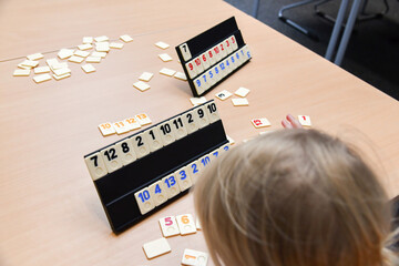 A little girl puts the chips with numbers in order.