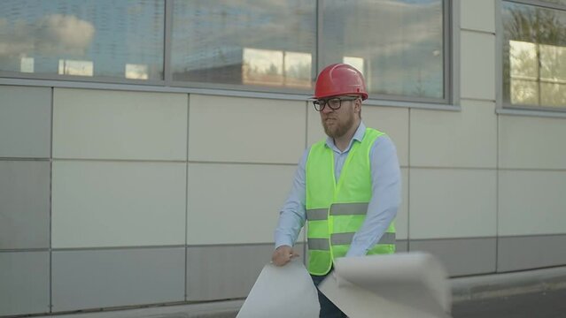 on a large construction site, an engineer is tearing a drawing apart