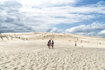 People explore in Lacka dune in Slowinski National Park in Poland. Traveling dune in sunny summer...