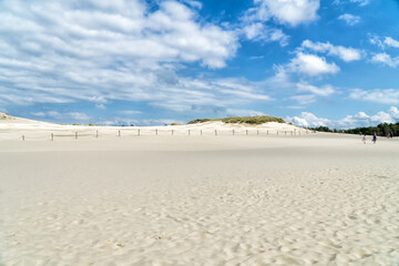 Lacka dune in Slowinski National Park in Poland. Traveling dune in sunny summer day. Sandy beach and blue sky with white clouds.