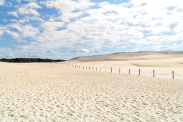 Lacka dune in Slowinski National Park in Poland, a miracle of nature. Traveling dune in sunny summer day. Sandy beach and blue sky with white clouds.
