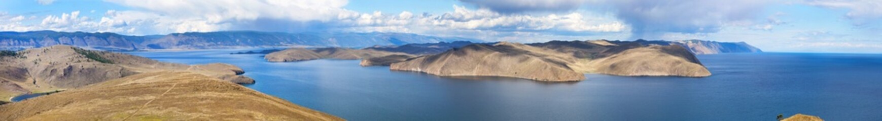 Panoramic view from the height of Cape Cross to the Olkhon Gate Strait, the steppe part of Olkhon Island and the horizon of Lake Baikal on a cloudy August day. Wide natural background, banner