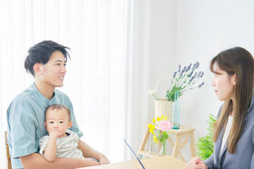 Obraz premium リビングで赤ちゃんの父親と話す女性外交員