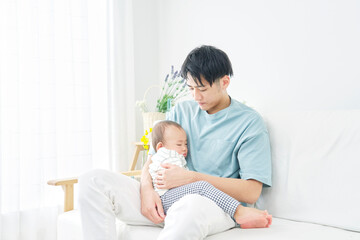 Obraz na płótnie Canvas リビングで父親に抱っこされて昼寝する赤ちゃん