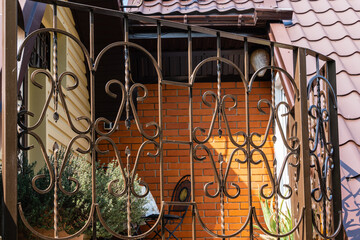 Fototapeta na wymiar Summer veranda on second floor of country house. Fencing of terrace with curly lattice. Back wall is made of facing bricks. Garden furniture. Table and two chairs in far corner. Secluded relaxation.