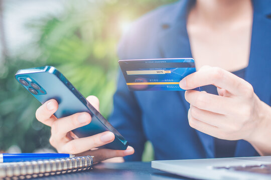Woman hand uses a cell phone and credit card to manage online shopping.