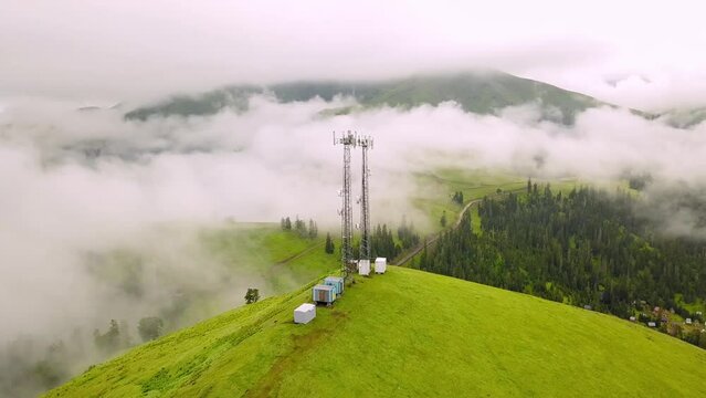 View from drone to GSM tower and radio communications in mountains in clouds. Cell tower. Base transceiver station. Wireless communication antenna transmitter. Bakhmaro, Georgia