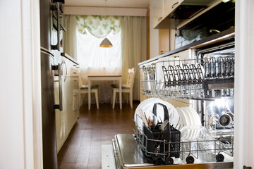 Dishwasher machine loaded with clean dishes. Modern scandinavian interior with kitchen appliances. 