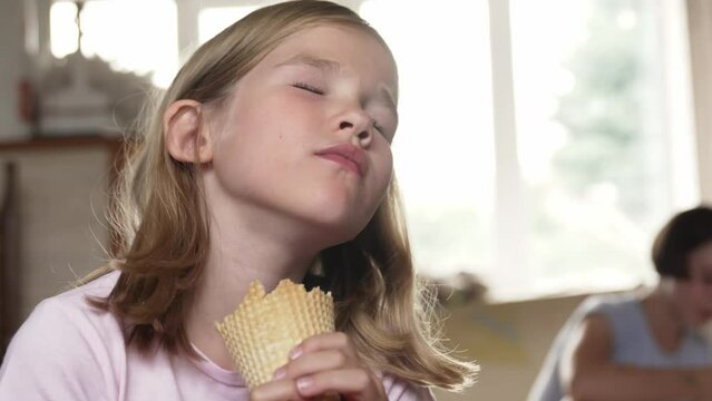a little girl eats ice cream in a waffle cone. favorite summer children's dessert.