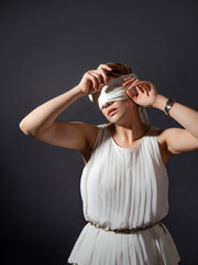 Close your eyes, hide from the truth, concept. An ancient heroine blindfolded, a young woman in a...