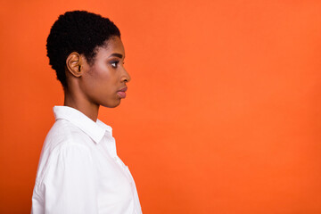 Profile side photo of serious emotion expression female look empty space thinking brainstorming isolated on orange color background