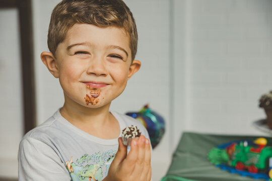 menino comendo bolo de chocolate e brigadeiro em anivers&aacute;rio