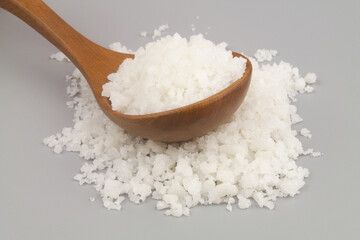 Salt in wooden spoon and on gray background	