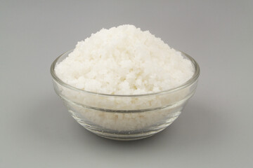 Glass bowl with sea salt on gray background.	