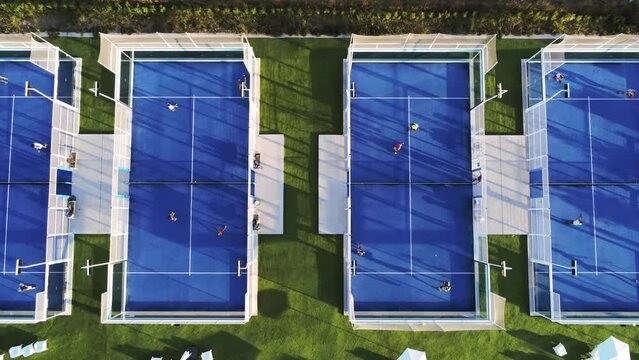 Overhead top view zoom in aerial shot of a blue Padel field in a sport centre in the city. Sport. Four players are playing together.