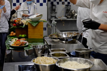 A thai chef cooking a pad thai during a masterclass. Paris, France.
