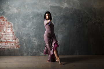 Young adult spanish woman dancing flamenco on gray vintage studio background