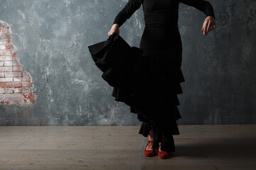 Young adult spanish woman dancing flamenco on gray vintage studio background legs close up