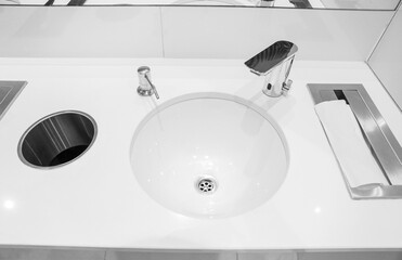 White sinks with paper towels, urns, soap and automatic faucets in a public restroom