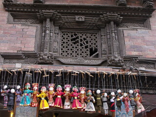Kathmandu, Nepal, August 20, 2011: Colorful puppets hang from the wall of an old building on a...