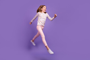 Fototapeta na wymiar Full length portrait of excited active pupil look run jump empty space isolated on purple color background
