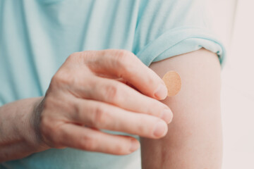 Vaccination elderly woman in doctor office with adhesive covid-19 vaccine plaster
