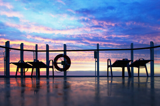 Blick auf an der Reling stehende Liegestühle im Sonnenaufgang, horizontal 