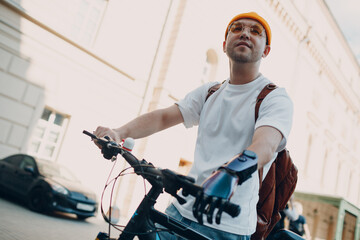 Young disabled man with artificial prosthetic hand in casual clothes riding bicycle