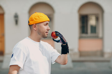 Young disabled man hold apple with artificial prosthetic hand in casual clothes