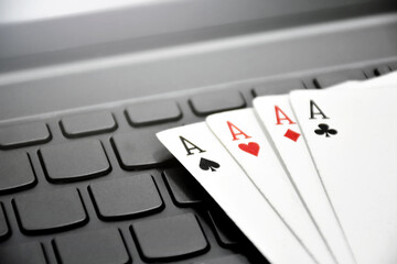 Paper cards on blank laptop keyboard, soft and selective focus, concept for playing cards online with other people at home and recreational activity.