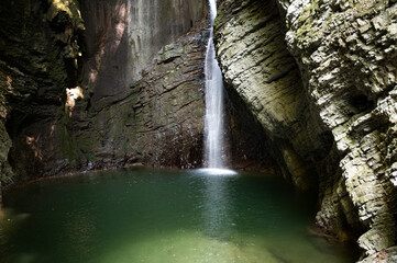 Beautiful waterfall kozjak falling into a green pool or lake
