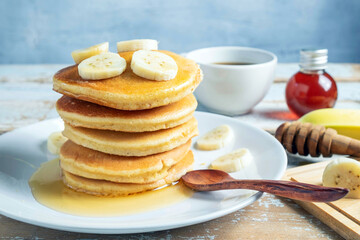 Stack of  banana pancakes with slices of fresh bananas, a Sweet Homemade Stack of Pancakes with Butter and Syrup for Breakfast in wooden background