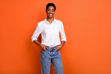Photo of cool cheerful successful businesswoman in white shirt and jeans isolated on orange color background