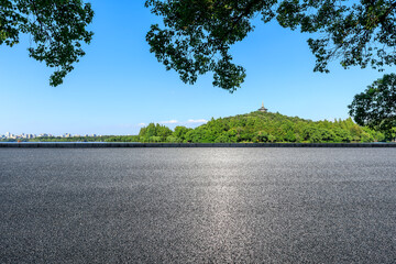 Empty asphalt road and green mountains with city skyline in Hangzhou, China.