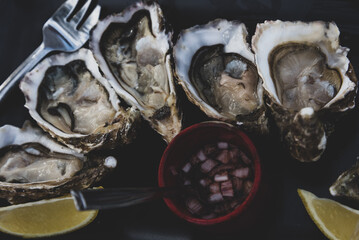 Fresh oyster platter served with classic mignonette sauce. Moody vintage seafood background