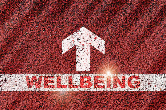 Wellbeing word on starting line with arrow on red road background. Health and wealth concept