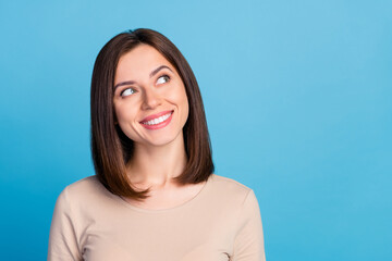 Portrait of pretty positive person beaming smile look interested empty space isolated on blue color background